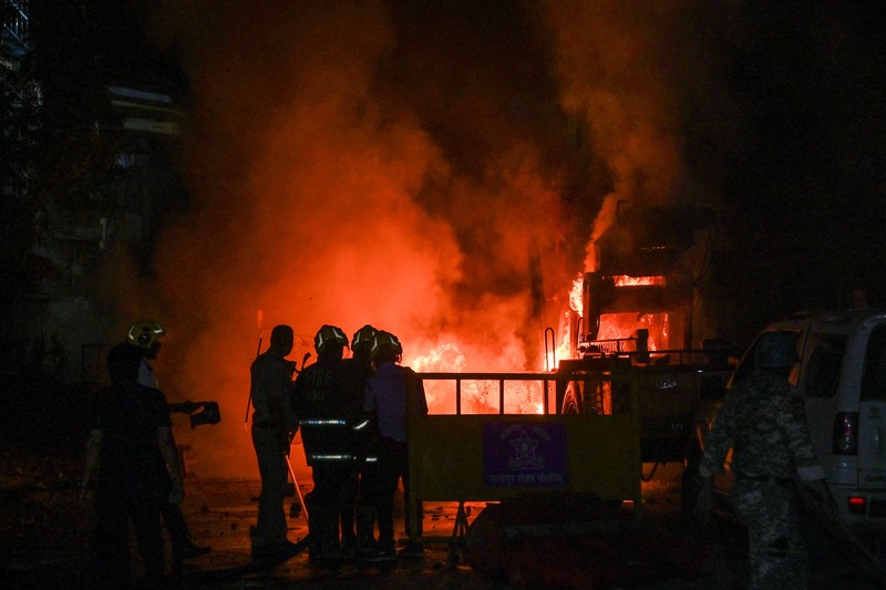 Seorang petugas pemadam kebakaran berdiri di dekat kendaraan yang terbakar setelah bentrokan di kawasan Chitnavis Park Square, Nagpur pada 17 Maret 2025. (AFP)