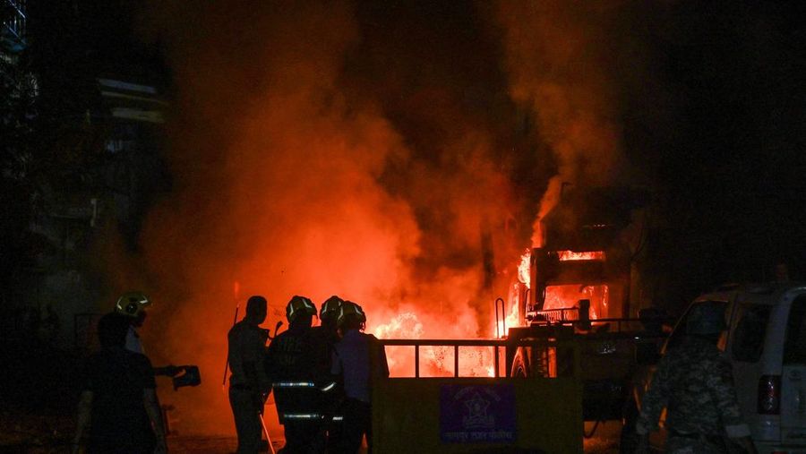 Seorang petugas pemadam kebakaran berdiri di dekat kendaraan yang terbakar setelah bentrokan di kawasan Chitnavis Park Square, Nagpur pada 17 Maret 2025. (AFP)