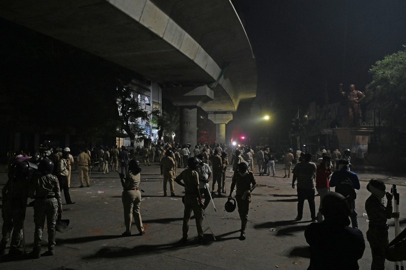 Seorang petugas pemadam kebakaran berdiri di dekat kendaraan yang terbakar setelah bentrokan di kawasan Chitnavis Park Square, Nagpur pada 17 Maret 2025. (AFP)