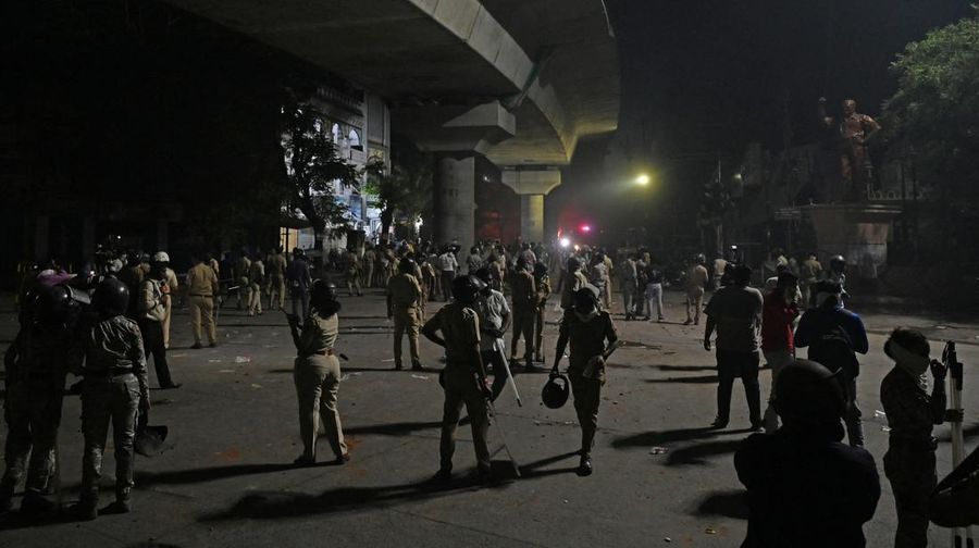 Seorang petugas pemadam kebakaran berdiri di dekat kendaraan yang terbakar setelah bentrokan di kawasan Chitnavis Park Square, Nagpur pada 17 Maret 2025. (AFP)