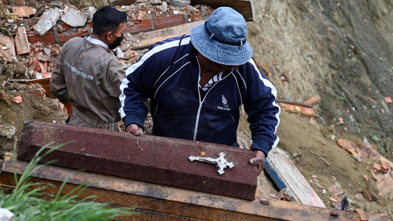 Orang-orang menemukan jenazah kerabat mereka setelah tanah longsor di pemakaman rahasia Ovejuyo yang disebabkan oleh hujan, di kotamadya Palca, Bolivia, 17 Maret 2025. (REUTERS/Claudia Morales)