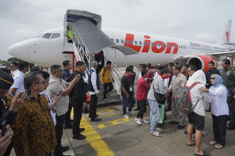 Warga Negara Indonesia yang pernah bekerja di pusat penipuan di Myanmar disambut petugas saat tiba dari Thailand, di Bandara Internasional Soekarno-Hatta di Tangerang, Indonesia, Selasa, 18 Maret 2025. (AP Photo/Tatan Syuflana, Pool)