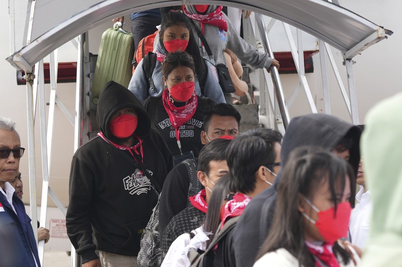 Warga Negara Indonesia yang pernah bekerja di pusat penipuan di Myanmar disambut petugas saat tiba dari Thailand, di Bandara Internasional Soekarno-Hatta di Tangerang, Indonesia, Selasa, 18 Maret 2025. (AP Photo/Tatan Syuflana, Pool)