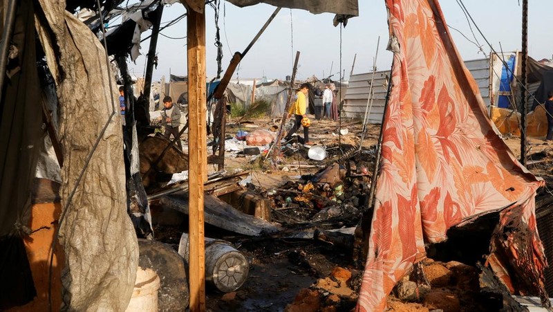 Warga Palestina memeriksa lokasi serangan Israel terhadap kamp tenda yang menampung orang-orang terlantar, di daerah Al-Mawasi, di Khan Younis di Jalur Gaza selatan, 18 Maret 2025. (REUTERS/Hatem Khaled)