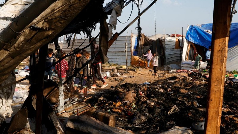 Warga Palestina memeriksa lokasi serangan Israel terhadap kamp tenda yang menampung orang-orang terlantar, di daerah Al-Mawasi, di Khan Younis di Jalur Gaza selatan, 18 Maret 2025. (REUTERS/Hatem Khaled)