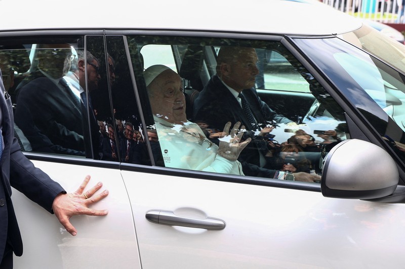 Orang-orang menonton Paus Fransiskus selama penampilan publik pertamanya dalam lima minggu, di layar lebar di Lapangan Santo Petrus, di Vatikan, 23 Maret 2025. (REUTERS/Matteo Minnella)