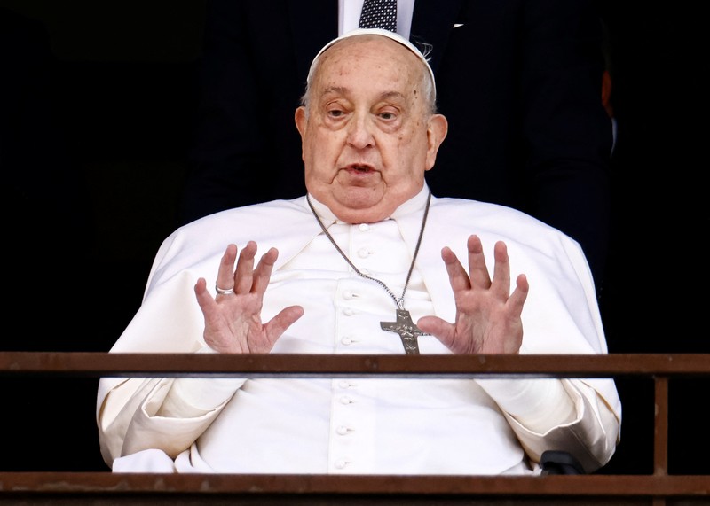 Orang-orang menonton Paus Fransiskus selama penampilan publik pertamanya dalam lima minggu, di layar lebar di Lapangan Santo Petrus, di Vatikan, 23 Maret 2025. (REUTERS/Matteo Minnella)