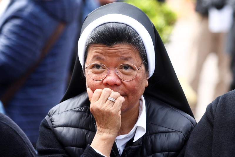Orang-orang menonton Paus Fransiskus selama penampilan publik pertamanya dalam lima minggu, di layar lebar di Lapangan Santo Petrus, di Vatikan, 23 Maret 2025. (REUTERS/Matteo Minnella)