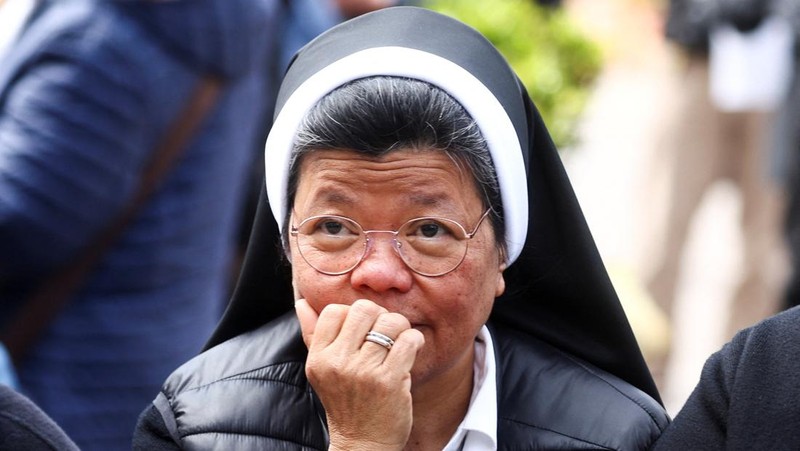 Orang-orang menonton Paus Fransiskus selama penampilan publik pertamanya dalam lima minggu, di layar lebar di Lapangan Santo Petrus, di Vatikan, 23 Maret 2025. (REUTERS/Matteo Minnella)