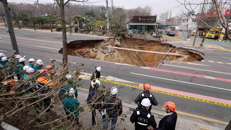Emergency workers stand near a sinkhole in a road, in Seoul, South Korea, March 25, 2025. Yonhap via REUTERS