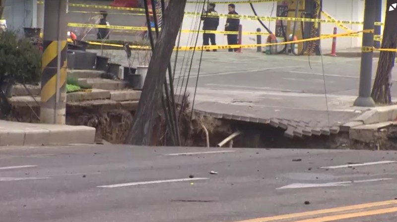 Emergency workers stand near a sinkhole in a road, in Seoul, South Korea, March 25, 2025. Yonhap via REUTERS