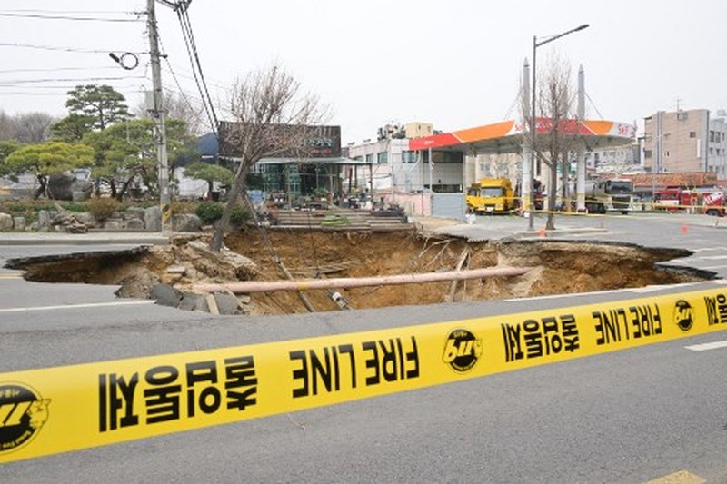 Emergency workers stand near a sinkhole in a road, in Seoul, South Korea, March 25, 2025. Yonhap via REUTERS