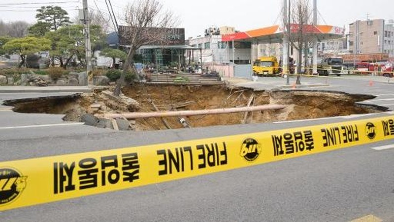 Emergency workers stand near a sinkhole in a road, in Seoul, South Korea, March 25, 2025. Yonhap via REUTERS
