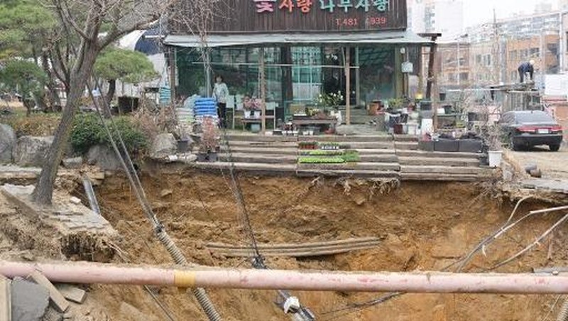 Emergency workers stand near a sinkhole in a road, in Seoul, South Korea, March 25, 2025. Yonhap via REUTERS
