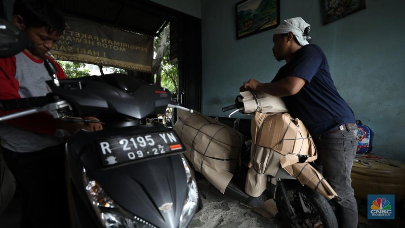 Pekerja membungkus sepeda motor dengan kardus di jasa pengiriman barang di kawasan Pasar Senen, Jakarta, Rabu (26/3/2025). (վ/Tri Susilo)