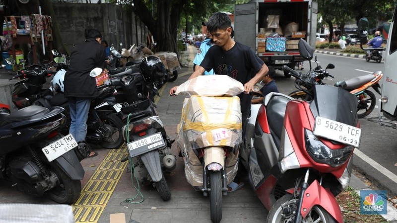 Pekerja membungkus sepeda motor dengan kardus di jasa pengiriman barang di kawasan Pasar Senen, Jakarta, Rabu (26/3/2025). (վ/Tri Susilo)