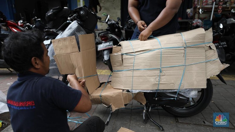 Pekerja membungkus sepeda motor dengan kardus di jasa pengiriman barang di kawasan Pasar Senen, Jakarta, Rabu (26/3/2025). (վ/Tri Susilo)