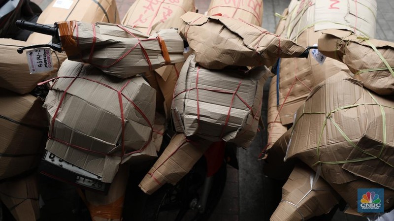 Pekerja membungkus sepeda motor dengan kardus di jasa pengiriman barang di kawasan Pasar Senen, Jakarta, Rabu (26/3/2025). (վ/Tri Susilo)