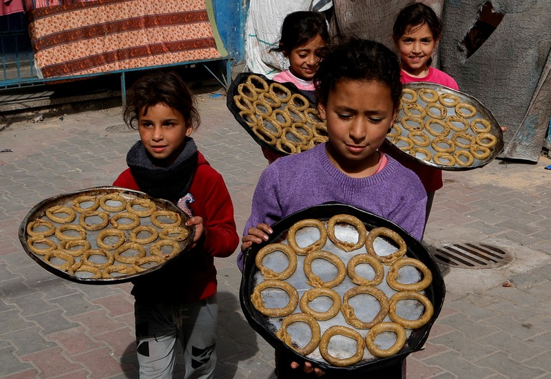 Perempuan Palestina yang mengungsi menyiapkan penganan tradisional untuk hari raya Idul Fitri yang menandai berakhirnya bulan puasa Ramadan, di Khan Younis di Jalur Gaza selatan pada 29 Maret 2025. (REUTERS/Hatem Khaled)