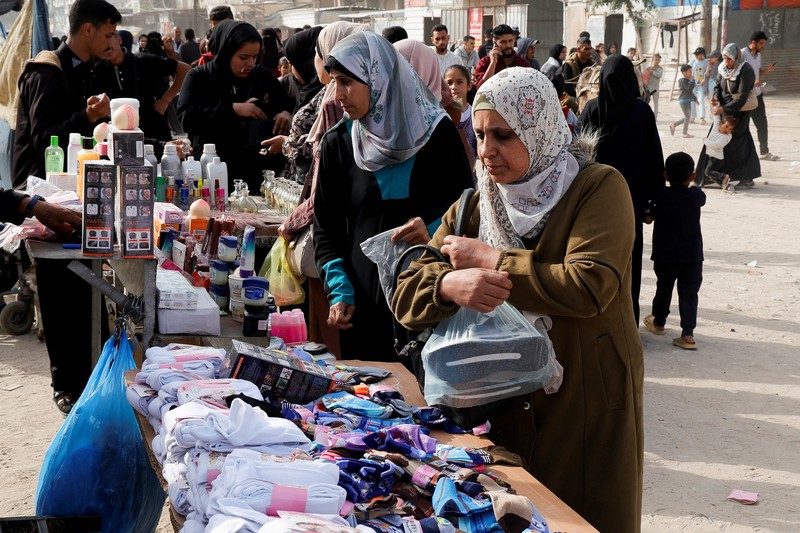 Perempuan Palestina yang mengungsi menyiapkan penganan tradisional untuk hari raya Idul Fitri yang menandai berakhirnya bulan puasa Ramadan, di Khan Younis di Jalur Gaza selatan pada 29 Maret 2025. (REUTERS/Hatem Khaled)