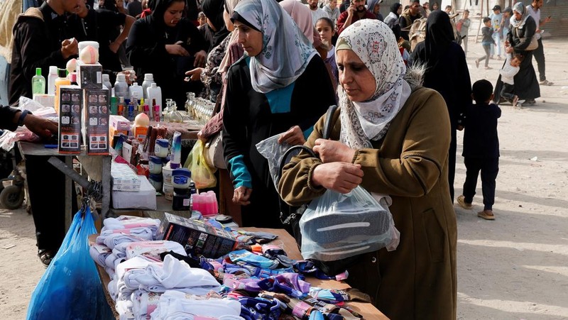 Perempuan Palestina yang mengungsi menyiapkan penganan tradisional untuk hari raya Idul Fitri yang menandai berakhirnya bulan puasa Ramadan, di Khan Younis di Jalur Gaza selatan pada 29 Maret 2025. (REUTERS/Hatem Khaled)