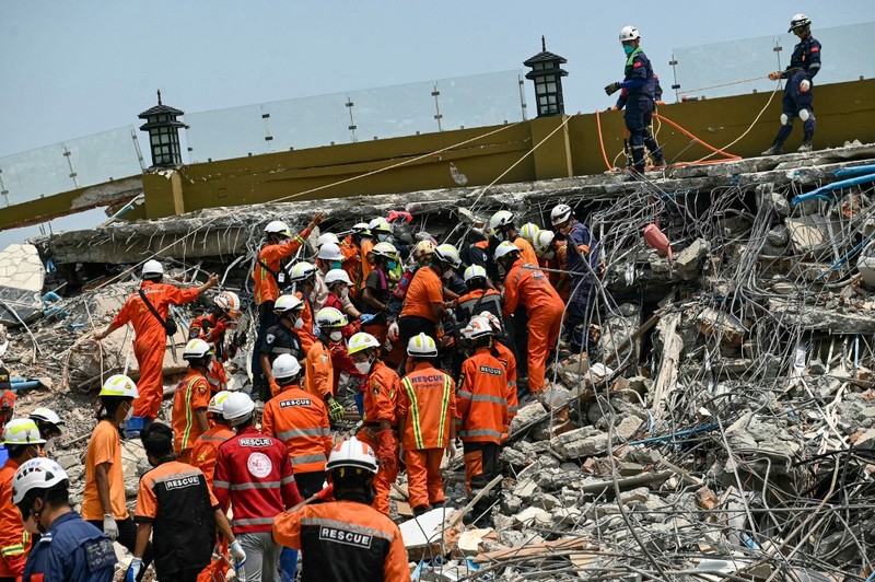 Tim penyelamat Myanmar dan Tiongkok membawa jenazah korban yang terjebak di bawah reruntuhan bangunan yang runtuh 'Sky Villa Condominium development' di Mandalay, Myanmar, Rabu (2/4/2025). (Sai Aung MAIN / AFP) Tim penyelamat Myanmar dan Tiongkok membawa jenazah korban yang terjebak di bawah reruntuhan bangunan yang runtuh 'Sky Villa Condominium development' di Mandalay, Myanmar, Rabu (2/4/2025). (Sai Aung MAIN / AFP)
