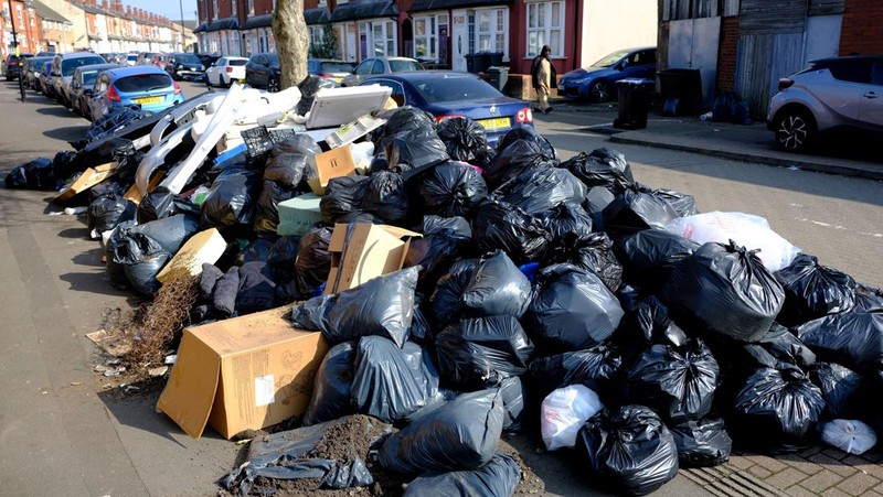 Seorang anak sekolah menutup hidungnya karena mencium bau tumpukan sampah yang menghalangi trotoar, saat aksi mogok pekerja tempat sampah Birmingham yang diwakili oleh serikat pekerja Unite memasuki minggu keempat, di Sparkhill, Birmingham, Inggris, 2 April 2025. (REUTERS/Jaimi Joy)