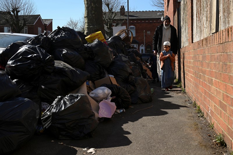 Seorang anak sekolah menutup hidungnya karena mencium bau tumpukan sampah yang menghalangi trotoar, saat aksi mogok pekerja tempat sampah Birmingham yang diwakili oleh serikat pekerja Unite memasuki minggu keempat, di Sparkhill, Birmingham, Inggris, 2 April 2025. Seorang anak sekolah menutup hidungnya karena mencium bau tumpukan sampah yang menghalangi trotoar, saat aksi mogok pekerja tempat sampah Birmingham yang diwakili oleh serikat pekerja Unite memasuki minggu keempat, di Sparkhill, Birmingham, Inggris, 2 April 2025. (REUTERS/Jaimi Joy)