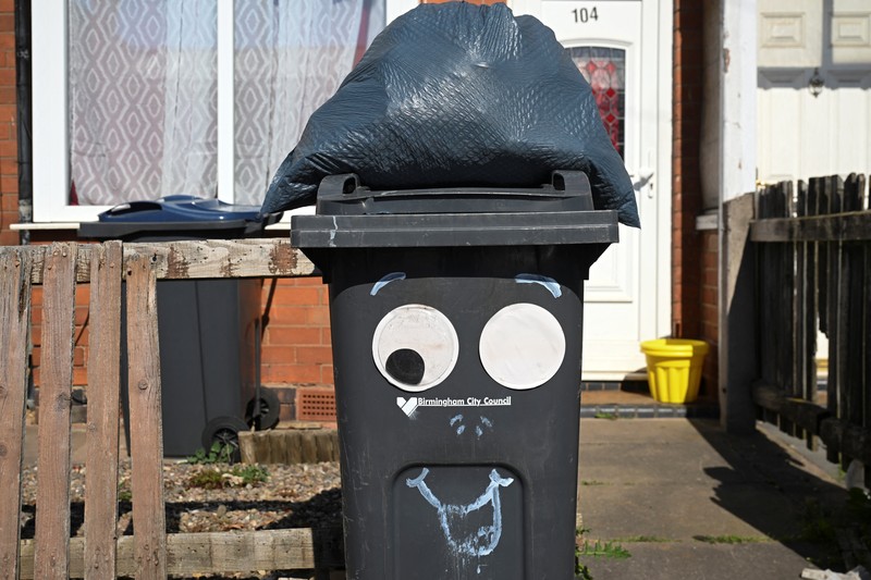Seorang anak sekolah menutup hidungnya karena mencium bau tumpukan sampah yang menghalangi trotoar, saat aksi mogok pekerja tempat sampah Birmingham yang diwakili oleh serikat pekerja Unite memasuki minggu keempat, di Sparkhill, Birmingham, Inggris, 2 April 2025. (REUTERS/Jaimi Joy)