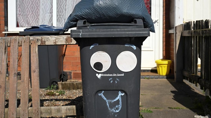 Seorang anak sekolah menutup hidungnya karena mencium bau tumpukan sampah yang menghalangi trotoar, saat aksi mogok pekerja tempat sampah Birmingham yang diwakili oleh serikat pekerja Unite memasuki minggu keempat, di Sparkhill, Birmingham, Inggris, 2 April 2025. (REUTERS/Jaimi Joy)