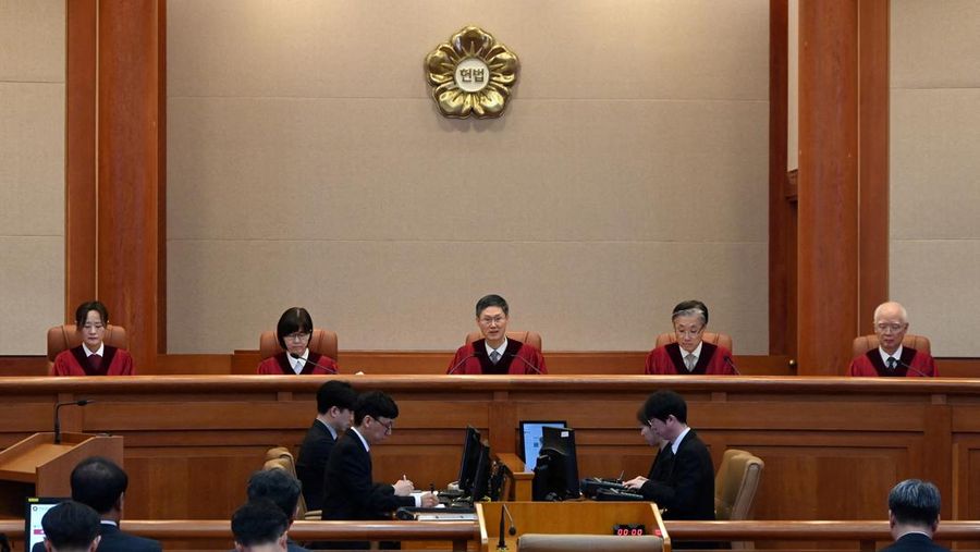 Orang-orang menonton laporan berita langsung sambil menunggu putusan Mahkamah Konstitusi atas pemakzulan Presiden Yoon Suk Yeol, di dekat Mahkamah Konstitusi di Seoul, Korea Selatan, 4 April 2025. (REUTERS/Kim Hong-Ji)