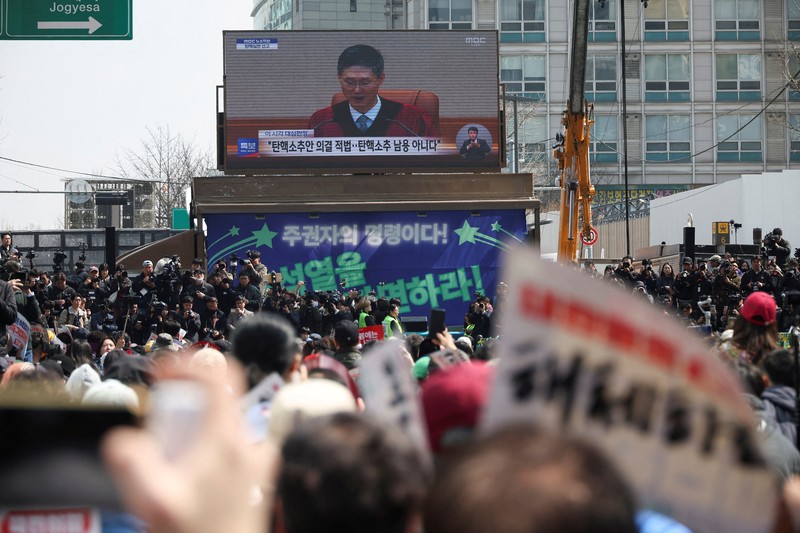Orang-orang menonton laporan berita langsung sambil menunggu putusan Mahkamah Konstitusi atas pemakzulan Presiden Yoon Suk Yeol, di dekat Mahkamah Konstitusi di Seoul, Korea Selatan, 4 April 2025. (REUTERS/Kim Hong-Ji) Orang-orang menonton laporan berita langsung sambil menunggu putusan Mahkamah Konstitusi atas pemakzulan Presiden Yoon Suk Yeol, di dekat Mahkamah Konstitusi di Seoul, Korea Selatan, 4 April 2025. (REUTERS/Kim Hong-Ji)