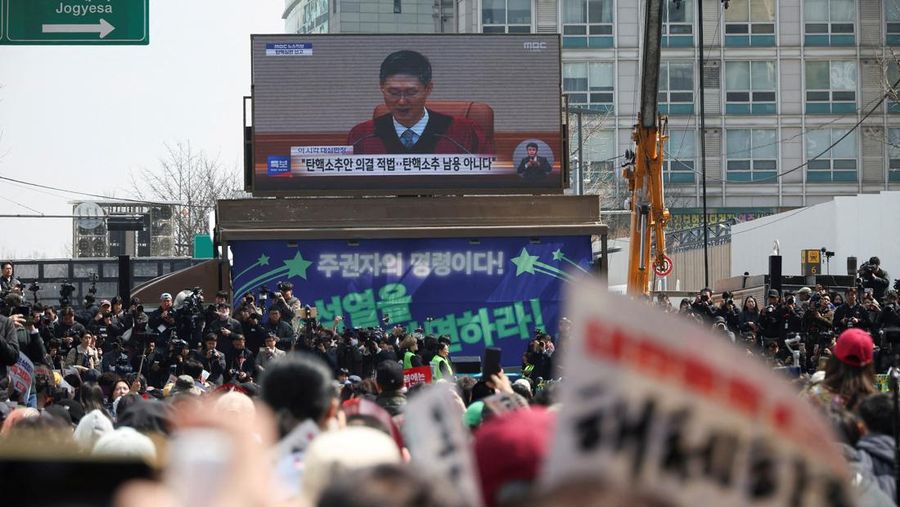 Orang-orang menonton laporan berita langsung sambil menunggu putusan Mahkamah Konstitusi atas pemakzulan Presiden Yoon Suk Yeol, di dekat Mahkamah Konstitusi di Seoul, Korea Selatan, 4 April 2025. (REUTERS/Kim Hong-Ji)