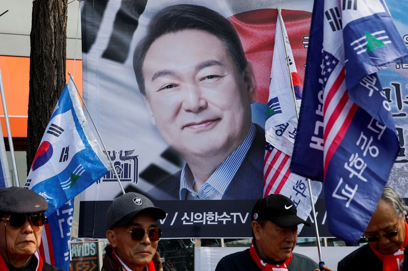 Orang-orang menonton laporan berita langsung sambil menunggu putusan Mahkamah Konstitusi atas pemakzulan Presiden Yoon Suk Yeol, di dekat Mahkamah Konstitusi di Seoul, Korea Selatan, 4 April 2025. (REUTERS/Kim Hong-Ji)