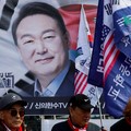 Para demonstran berdiri di depan spanduk bergambar Yoon Suk Yeol saat orang-orang menunggu putusan Mahkamah Konstitusi atas pemakzulan Presiden Yoon Suk Yeol, di dekat kediamannya di Seoul, Korea Selatan, 4 April 2025. (REUTERS/Kim Soo-hyeon)