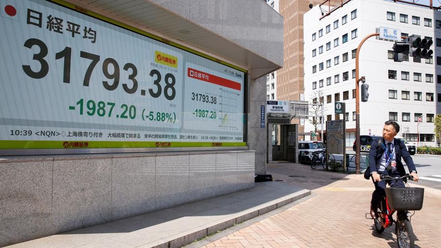 Seorang pria berjalan melewati papan harga saham di sebuah perusahaan pialang di Tokyo, Jepang, 7 April 2025. REUTERS/Androniki Christodoulou