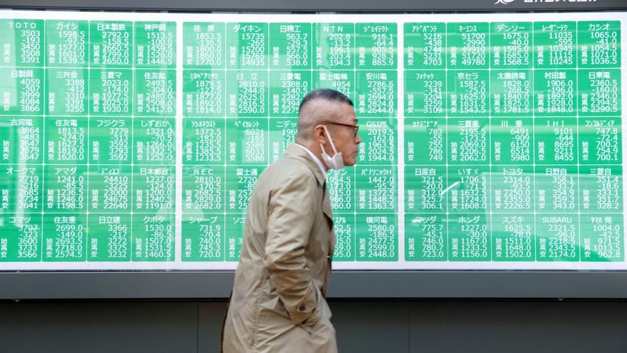 Seorang pria berjalan melewati papan harga saham di sebuah perusahaan pialang di Tokyo, Jepang, 7 April 2025. REUTERS/Androniki Christodoulou
