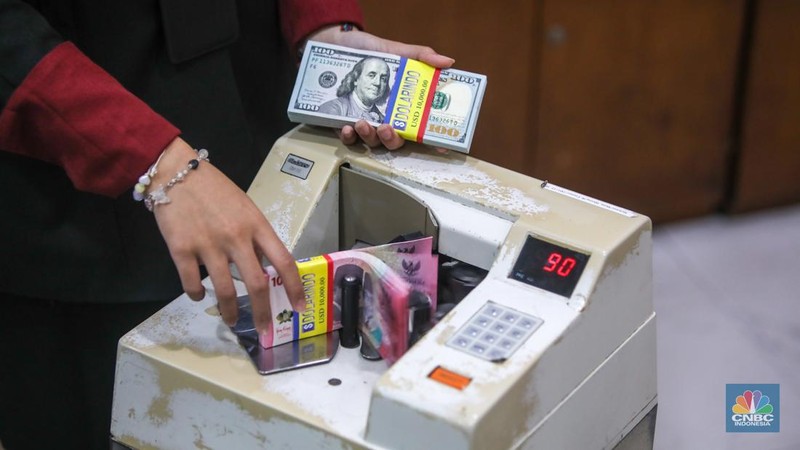 Petugas menjunjukkan uang pecahan dolar AS dan rupiah di Dolarindo Money Changer, Jakarta, Selasa (8/4/2025). (CNBC Indonesia/Faisal Rahman)
