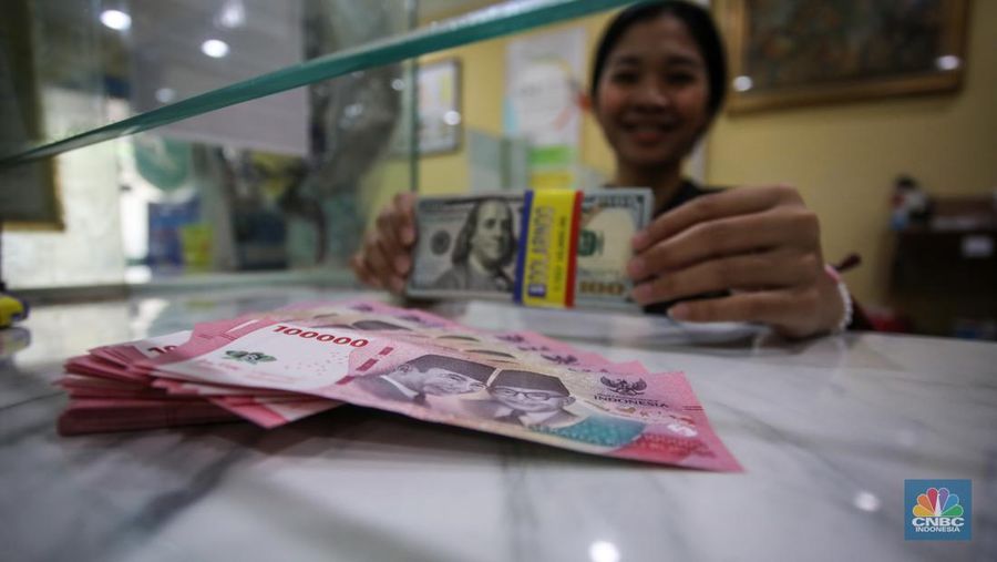 Petugas menjunjukkan uang pecahan dolar AS dan rupiah di Dolarindo Money Changer, Jakarta, Selasa (8/4/2025). (CNBC Indonesia/Faisal Rahman)