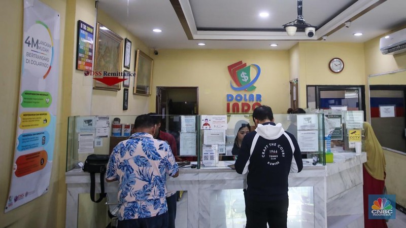 Petugas menjunjukkan uang pecahan dolar AS dan rupiah di Dolarindo Money Changer, Jakarta, Selasa (8/4/2025). (CNBC Indonesia/Faisal Rahman)