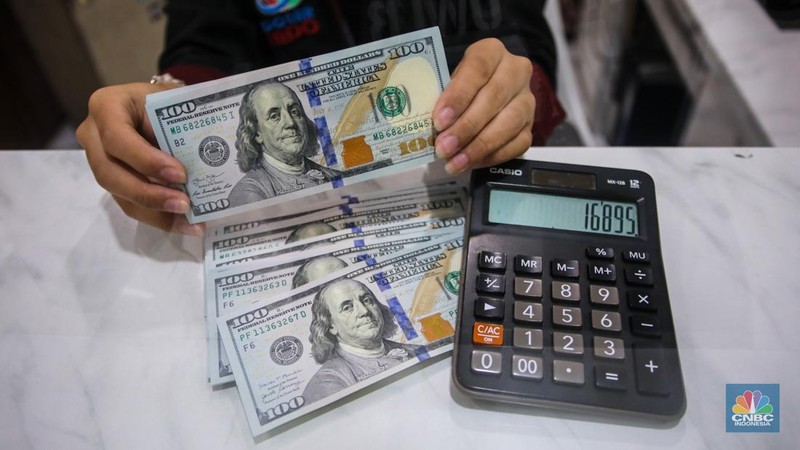 Petugas menjunjukkan uang pecahan dolar AS dan rupiah di Dolarindo Money Changer, Jakarta, Selasa (8/4/2025). (CNBC Indonesia/Faisal Rahman)