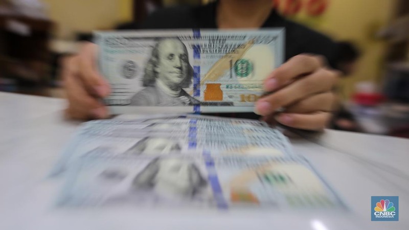Petugas menjunjukkan uang pecahan dolar AS dan rupiah di Dolarindo Money Changer, Jakarta, Selasa (8/4/2025). (CNBC Indonesia/Faisal Rahman)