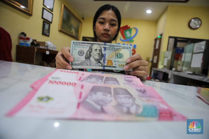 Petugas menjunjukkan uang pecahan dolar AS dan rupiah di Dolarindo Money Changer, Jakarta, Selasa (8/4/2025). Petugas menjunjukkan uang pecahan dolar AS dan rupiah di Dolarindo Money Changer, Jakarta, Selasa (8/4/2025). (CNBC Indonesia/Faisal Rahman)