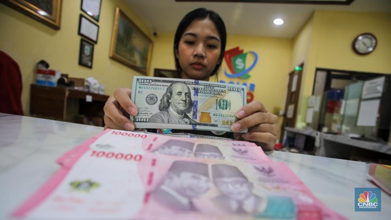 Petugas menjunjukkan uang pecahan dolar AS dan rupiah di Dolarindo Money Changer, Jakarta, Selasa (8/4/2025). (CNBC Indonesia/Faisal Rahman)