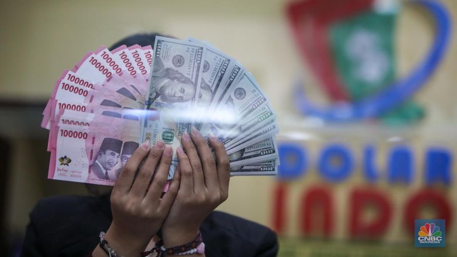 Petugas menjunjukkan uang pecahan dolar AS dan rupiah di Dolarindo Money Changer, Jakarta, Selasa (8/4/2025). (CNBC Indonesia/Faisal Rahman)