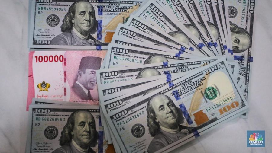 Petugas menjunjukkan uang pecahan dolar AS dan rupiah di Dolarindo Money Changer, Jakarta, Selasa (8/4/2025). (CNBC Indonesia/Faisal Rahman)