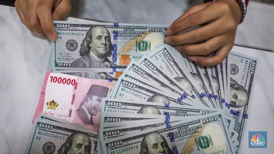 Petugas menjunjukkan uang pecahan dolar AS dan rupiah di Dolarindo Money Changer, Jakarta, Selasa (8/4/2025). (CNBC Indonesia/Faisal Rahman)