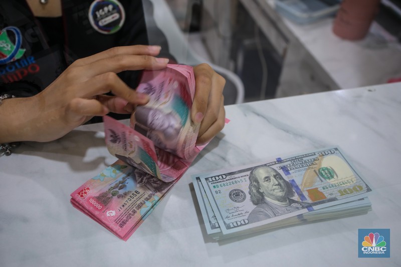 Petugas menjunjukkan uang pecahan dolar AS dan rupiah di Dolarindo Money Changer, Jakarta, Selasa (8/4/2025). Petugas menjunjukkan uang pecahan dolar AS dan rupiah di Dolarindo Money Changer, Jakarta, Selasa (8/4/2025). (CNBC Indonesia/Faisal Rahman)