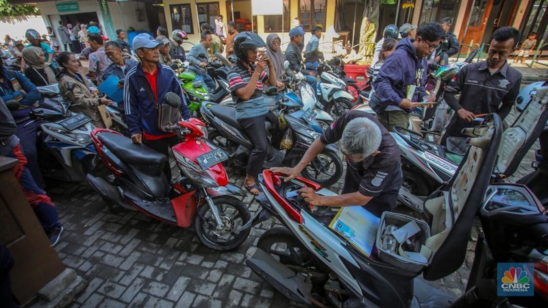 Warga antre untuk melakukan pemeriksaan fisik kendaraan wajib pajak untuk pengurusan pembayaran pajak kendaraan bermotor di kantor Samsat Ciputat, Tangerang Selatan, Banten, Jumat (11/4/2025). (CNBC Indonesia/Faisal Rahman)