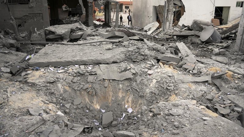 Palestinians inspect the damage caused by an Israeli army targeted strike that killed at least three people in Deir al-Balah, central Gaza Strip, Sunday, April 13, 2025. (AP Photo/Abdel Kareem Hana)